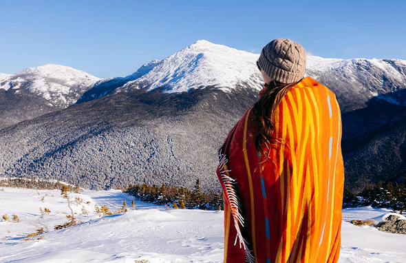 Woman wrapped in a blanket looking at the mountain view